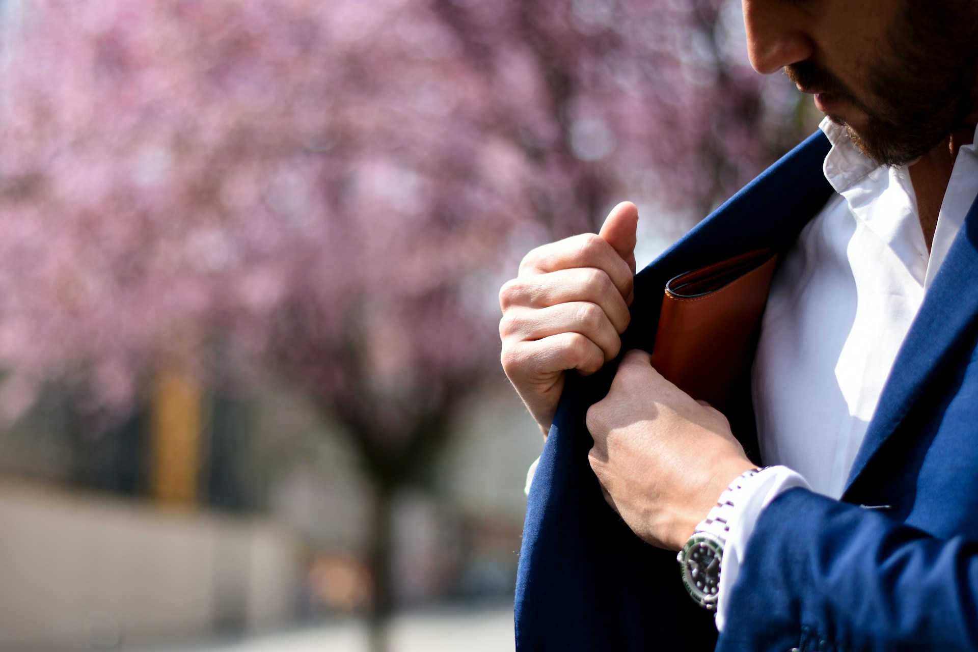 a man reaching into his jacket pocket, wearing a silver watch